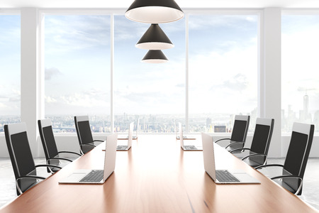 Modern meeting room with a wooden table with a laptop and hanging lampsの写真素材