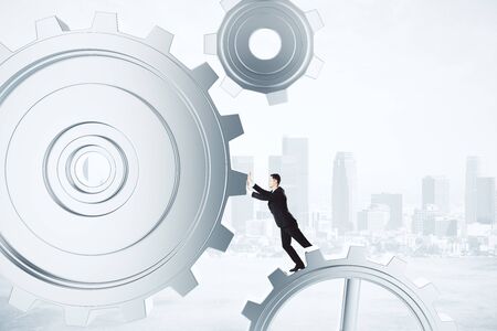 Businessman pushing gears in the mechanismの写真素材