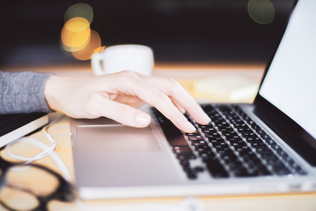 Girl typing in laptop with blank screen, cup of coffee and eyeglasses, mock upの写真素材