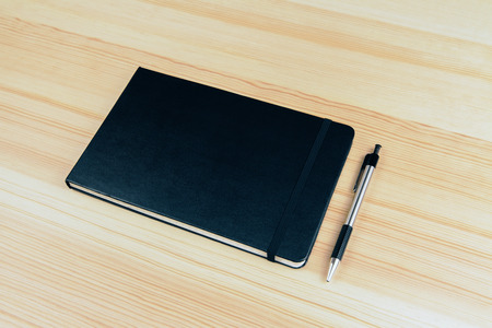 Blank cover of notebook with pen on wooden table, mock upの写真素材
