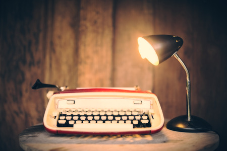 Vintage typewriter with lamp on wooden table at wooden wall backgroundの写真素材