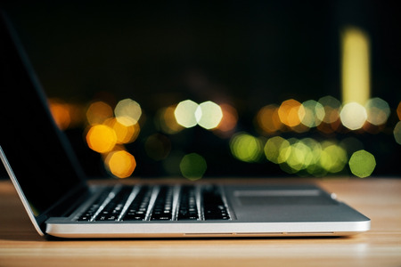 Opened laptop on wooden table at night, close upの写真素材