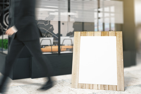 Square board standing outside building and a passing by businessman. Mock up, 3D Renderの写真素材