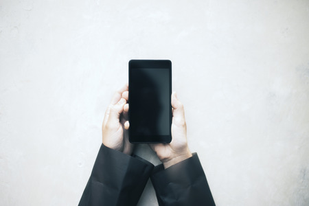 Hands holding a blank black smartphone on white background. Mock up