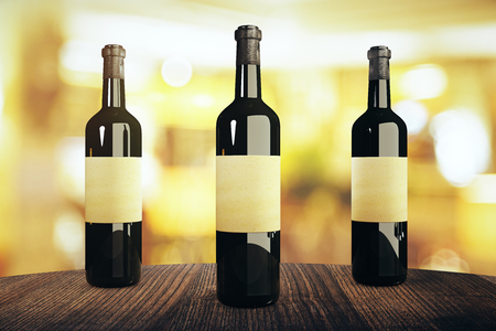 Three wine bottles with blank labels on wooden table and blurry background. Mock up, 3D Renderingの写真素材