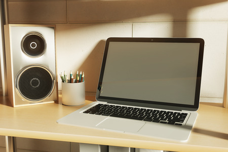 Closeup of blank laptop on creative desktop with loudspeaker and pencils. Mock up, 3D Rendering