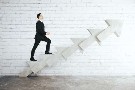 Success concept with businessman walking up abstract concrete arrow stairs on white brick background. 3D Renderingの写真素材