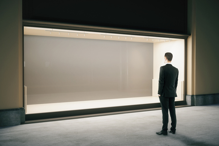 Businessman looking at empty showcase at night. Mock up, 3D Renderingの写真素材