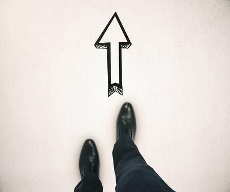 Guidance concept with businessman feet and arrow sketch showing direction on light groundの写真素材