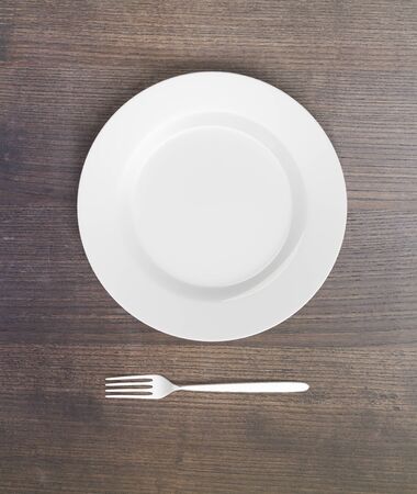 Top view of empty plate and fork on dark wooden table. Mock up, 3D Rendering