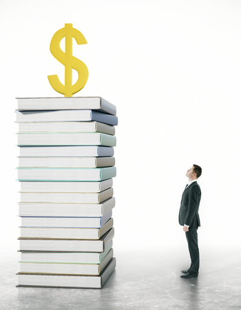 Businessman looking at dollar sign on top of book pile. Grey background. Financial growth and education concept. 3D Renderingの写真素材
