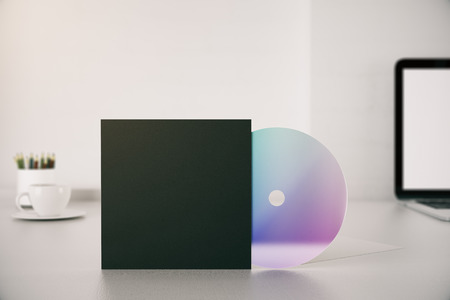 Closeup of empty black CD cover on desktop with laptop, coffee cup and pencils. Mock up, 3D Renderingの写真素材