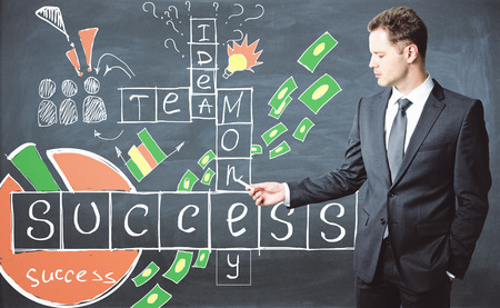 Businessman in suit solving crossword puzzle drawn on chalkboard. Success conceptの写真素材