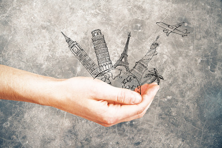 Male hand holding abstract sketch of landmarks and airplane on dark concrete background. Travel conceptの写真素材