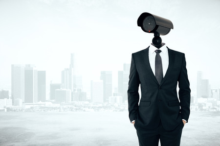 Business security management concept. Businessman with CCTV camera instead of head on abstract city background with copyspaceの写真素材