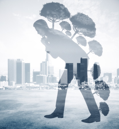 Abstract image of businessman silhouette with trees walking on city background. Growth concept. Double exposureの写真素材