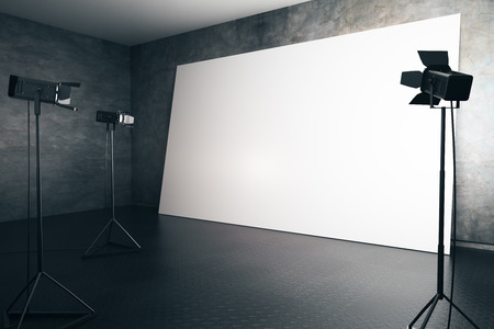 Concrete interior with blank white billboard and professional lighting equipment. Photo studio...