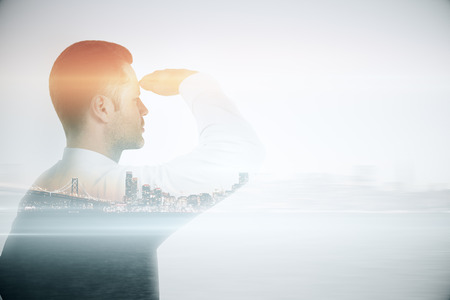 Young man looking into the distance on city background with copyspace. Research concept. Double...