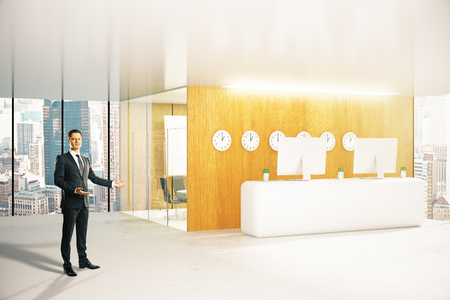 Young businessman showing modern reception desk with equipment and city view. 3D Renderingの写真素材
