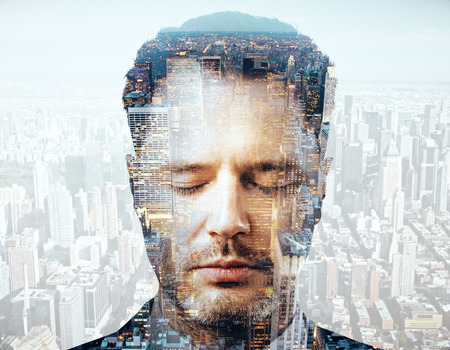 Close up portrait of handsome young businessman on city background. Double exposure. Brainstorming...
