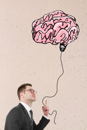 Businessman holding abstract human brain lamp balloon on light background. Brainstorming conceptの写真素材