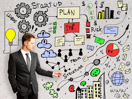 Businessman with creative business sketch on concrete wall background. Startup conceptの写真素材