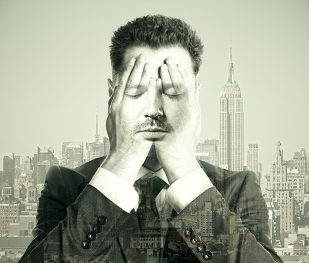 Businessman covering face with hands on city background. Double exposureの写真素材