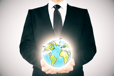 Businessman holding creative globe sketch on light background. Environment protection conceptの写真素材