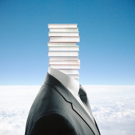 Book pile headed businessman in suit on sky background. Education conceptの写真素材