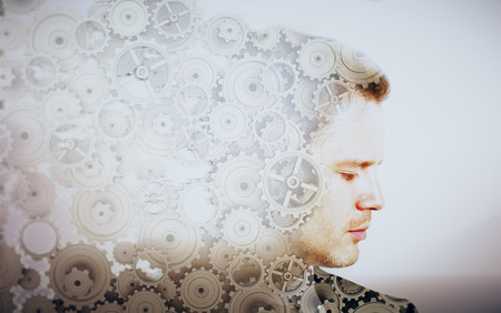 Side portrait of young businessman with cogwheels on light background. Double exposureの写真素材