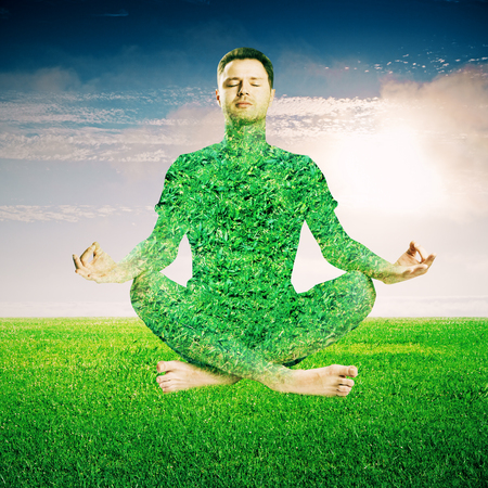 Meditating green grass man on sky background.の写真素材