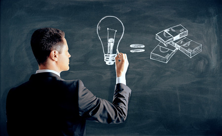 Man drawing creative lamp and money sketch on chalkboard.の写真素材