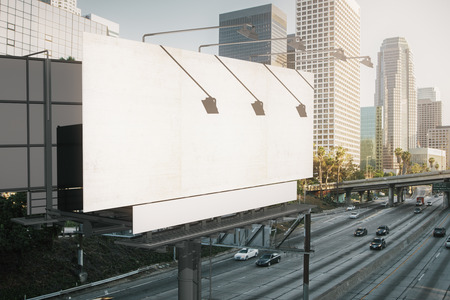 Empty white billboard on modern city background. Retail, advertisement concept. Side view. Mock up,...