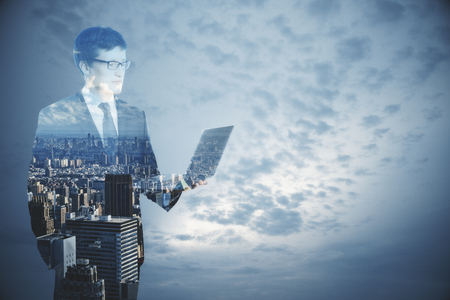 Businessman using laptop on abstract city and sky background with copy space. Communication conceptの写真素材
