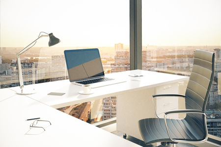 Office desktop with blank laptop in interior with panoramic city view and daylight. Mock up, 3D Renderingの写真素材