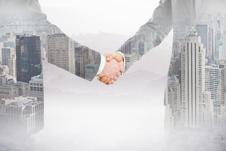 People shaking hands on city background. Teamwork concept. Double exposureの写真素材