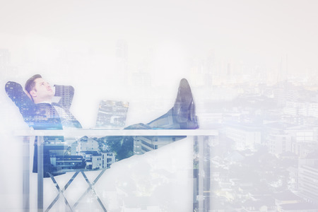 Relaxing businessman at workplace on creative city background. Double exposure. Success conceptの写真素材