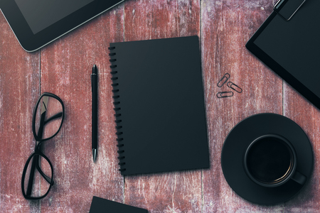 Top view of red wood office table with black notepad, coffee cup, pen, glasses, clips, tablets and other items. Workplace concept. Mock up, 3D Renderingの写真素材