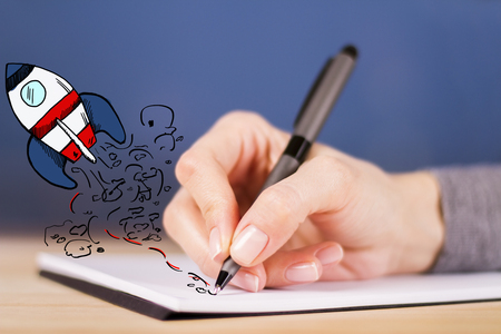 Female hand drawing abstract launching spaceship in notepad. Start up conceptの写真素材