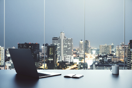 Creative desktop with open laptop, notepad, coffee cup and city view. 3D Renderingの写真素材