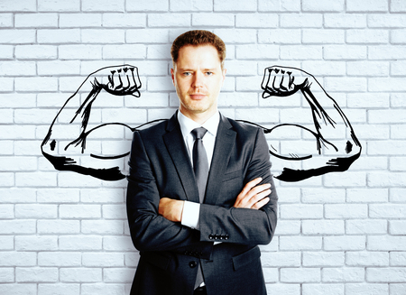 Confident businessman with drawn muscly hands on brick background. Strength conceptの写真素材