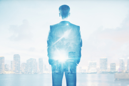 Back view of young businessperson on abstract city background with daylight and business chart arrow. Income concept. Double exposureの写真素材