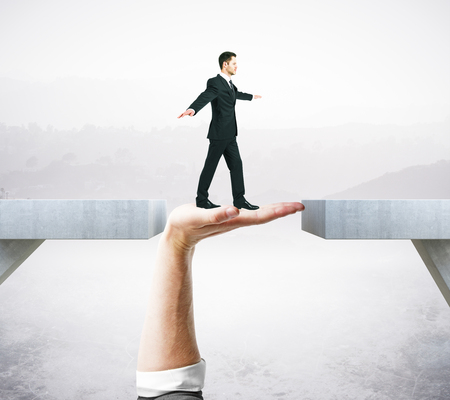 Businessman crossing abstract hand bridge on grey background. Help conceptの写真素材