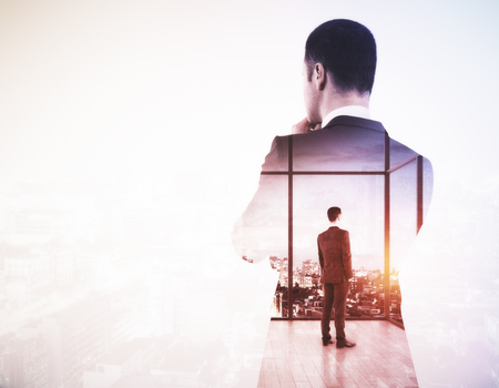 Back view of young businessman looking into the distance on light city background with copy space. Research concept. Double exposureの写真素材