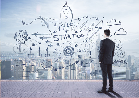 Back view of young businessman looking at creative business sketch on city background. Startup, targeting and teamwork conceptの写真素材