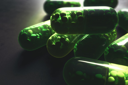 Close up of green pill capsules on concrete background. Medicine, prescription drugstore concept. 3D Renderingの写真素材