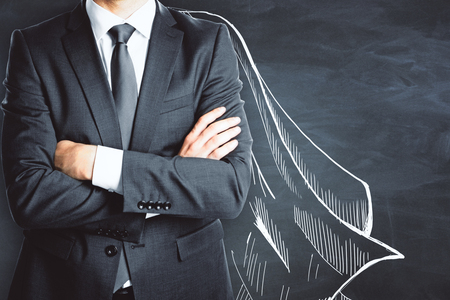 Businessman with drawn cape on chalkboard wall background. Protection conceptの写真素材