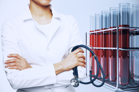 Female doctor with stethoscope and flasks with red liquid. Medicine conceptの写真素材