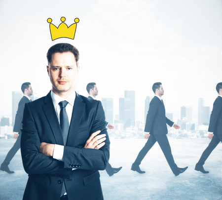 Confident businessman with folded arms and drawn crown. Walking people on city background. Leader conceptの写真素材