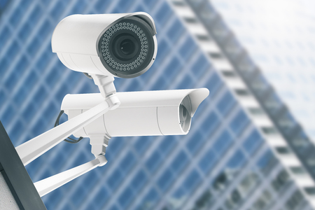 Close up of CCTV cameras with blurry modern glass building in the background. Electronics concept. 3D Renderingの写真素材